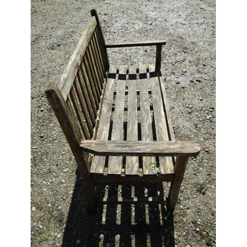 1053 - A weathered teak two seat garden bench with slatted seat and back (af) 130 cm wide