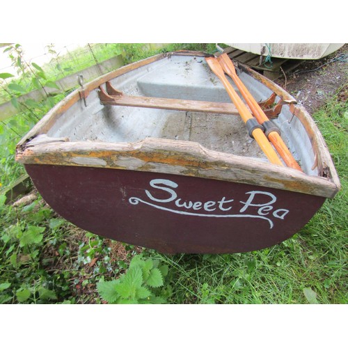 1110 - A small painted rowing boat with fibreglass hull and wood trim named Sweet Pea, complete with a pair... 