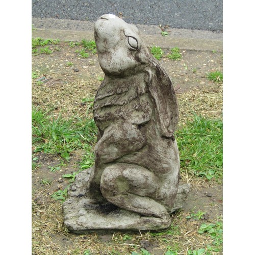 1122 - A weathered cast composition stone garden ornament in the form of a seated moongazing hare, 47 cm hi... 