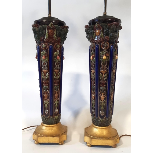 30 - A tall and impressive pair of majolica type table lamps, each with articulated twin lights over tape... 