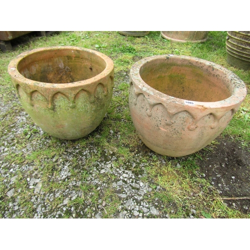 1085 - A matched pair of weathered terracotta squat oviform planters with repeating arched moulded gothic r... 