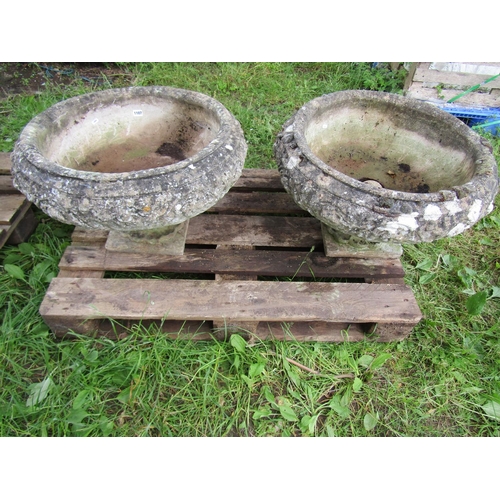 1107 - A pair of weathered cast composition stone garden urns , the squat circular bowls with foliate relie... 