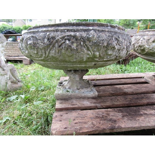 1107 - A pair of weathered cast composition stone garden urns , the squat circular bowls with foliate relie... 