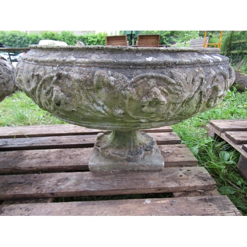 1107 - A pair of weathered cast composition stone garden urns , the squat circular bowls with foliate relie... 