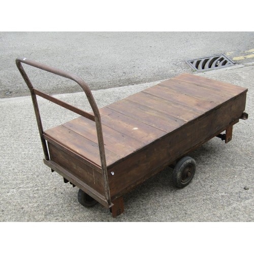 1687 - A vintage four wheeled platform trolley with wooden bed and tubular steel handle, the bed 130 x 56 c... 