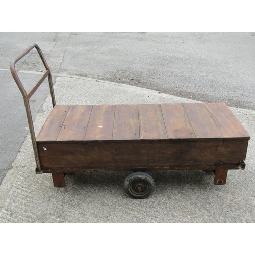 1687 - A vintage four wheeled platform trolley with wooden bed and tubular steel handle, the bed 130 x 56 c... 