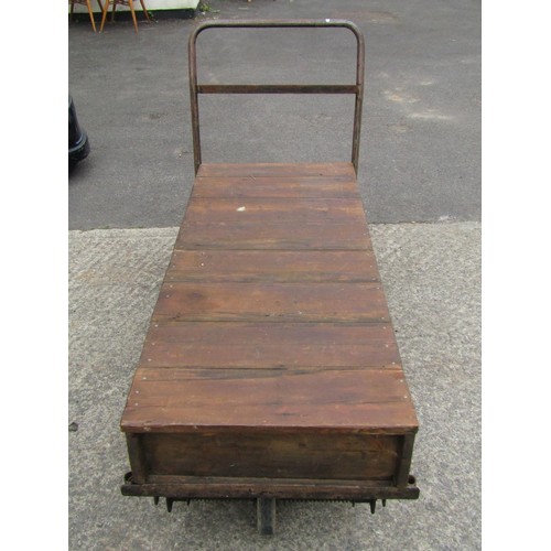 1687 - A vintage four wheeled platform trolley with wooden bed and tubular steel handle, the bed 130 x 56 c... 