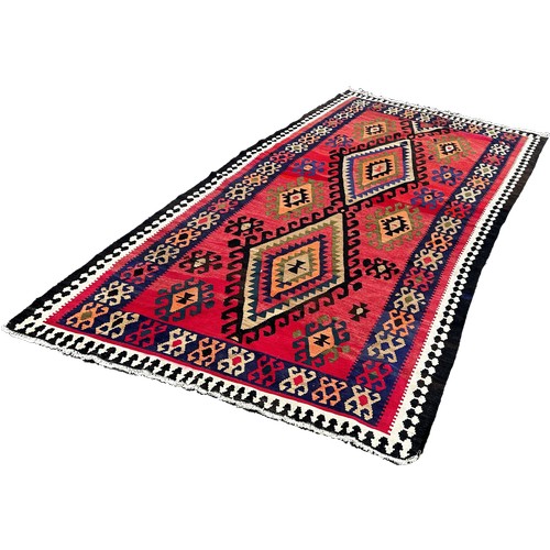 1758 - A Kilim with all over geometric medallion patterns on a  red ground 314cm x 155cm