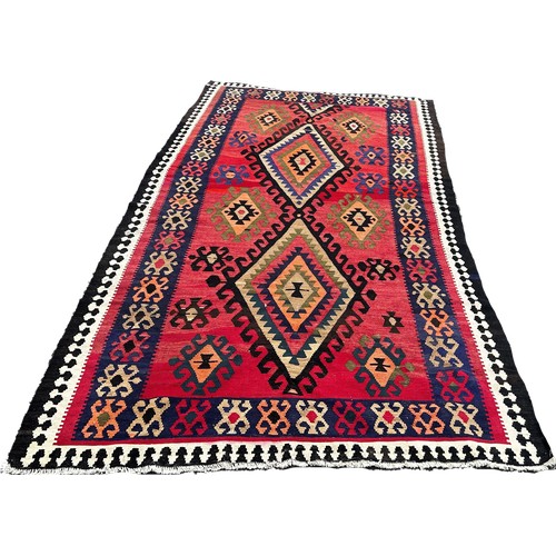 1758 - A Kilim with all over geometric medallion patterns on a  red ground 314cm x 155cm