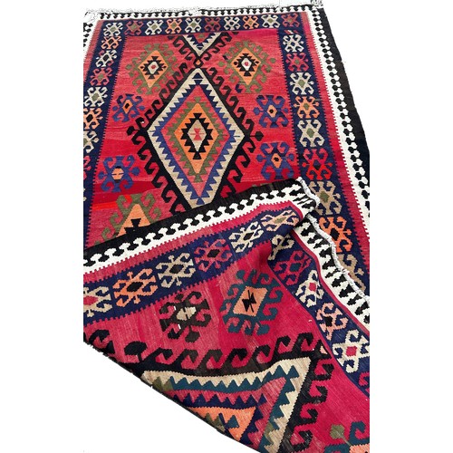 1758 - A Kilim with all over geometric medallion patterns on a  red ground 314cm x 155cm