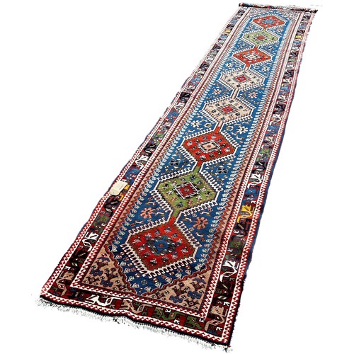 1755 - A Persian Runner with a central row of eight interlocking medallions on a dark blue ground, 380 x 84... 