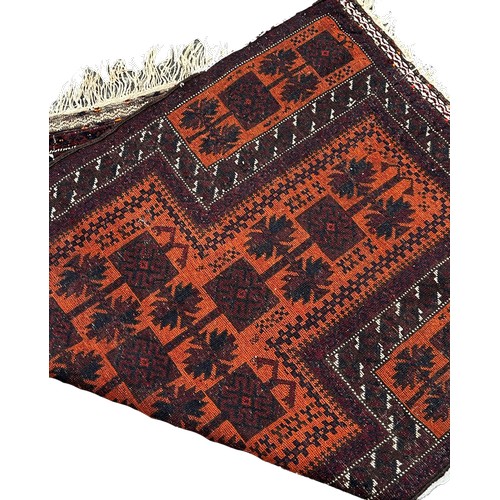 1771 - A Baluch Rug with black interlocking squares on an orange ground, 140 x 80cm approximately