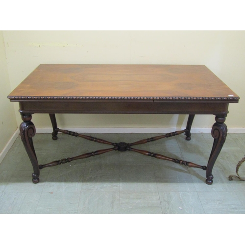 1717 - A walnut dining table of rectangular form with figured top and moulded edge raised on scrolled cabri... 