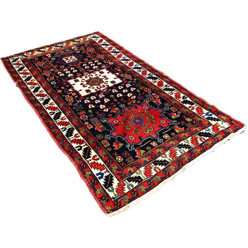 1777 - An Antique Persian Karaja rug with a central cream medallion with floral decoration on a blue ground... 