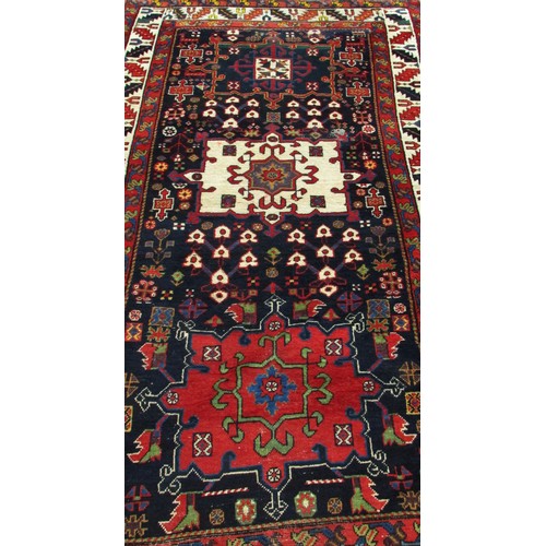 1777 - An Antique Persian Karaja rug with a central cream medallion with floral decoration on a blue ground... 