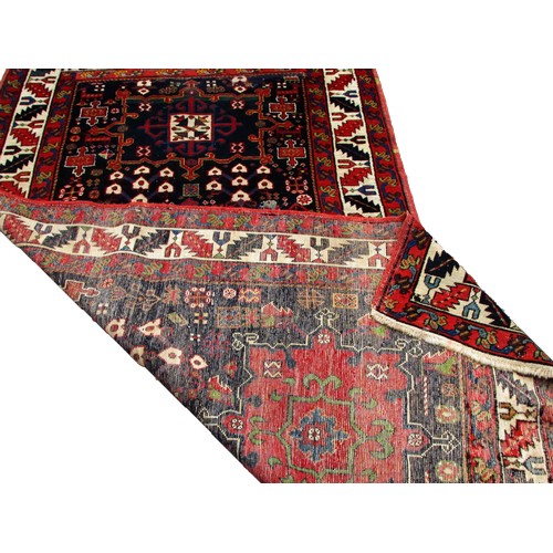 1777 - An Antique Persian Karaja rug with a central cream medallion with floral decoration on a blue ground... 