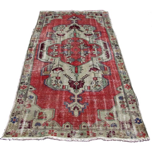 1779 - An old and faded Oushak rug with an extended central panel of stylised flowers, 220cm x 115cm approx... 