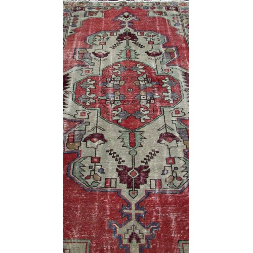 1779 - An old and faded Oushak rug with an extended central panel of stylised flowers, 220cm x 115cm approx... 