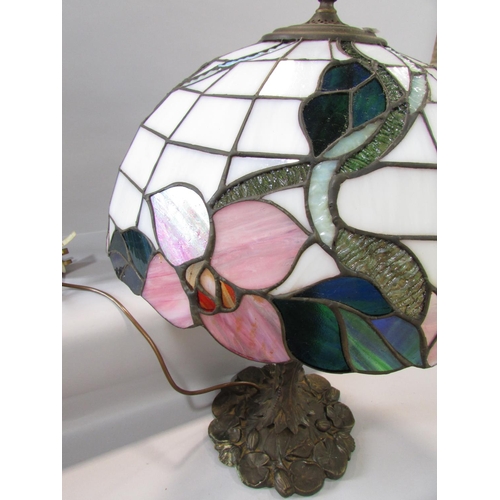 527 - A Tiffany style table lamp with a floral “leaded” shade on a naturalistic bronzed base.