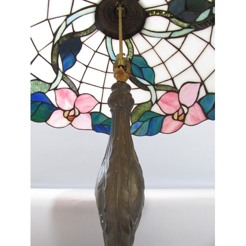 527 - A Tiffany style table lamp with a floral “leaded” shade on a naturalistic bronzed base.