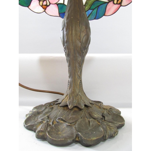 527 - A Tiffany style table lamp with a floral “leaded” shade on a naturalistic bronzed base.