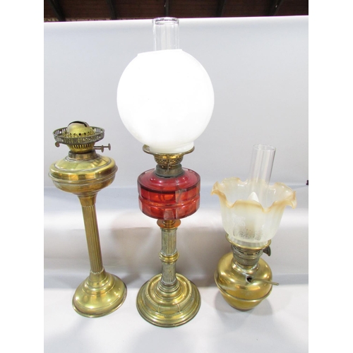 556 - A Victorian brass column oil lamp with a cracked cranberry red font and an opaque shade, together wi... 