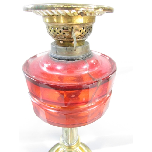 556 - A Victorian brass column oil lamp with a cracked cranberry red font and an opaque shade, together wi... 