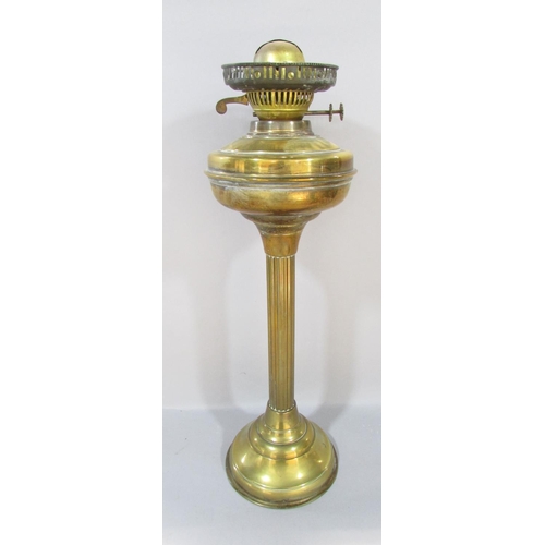 556 - A Victorian brass column oil lamp with a cracked cranberry red font and an opaque shade, together wi... 