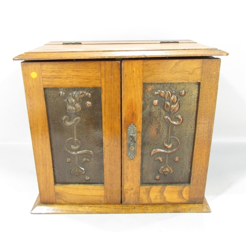 565 - An Arts and Crafts smokers cabinet with copper panelled doors opening to reveal two drawers, three p... 