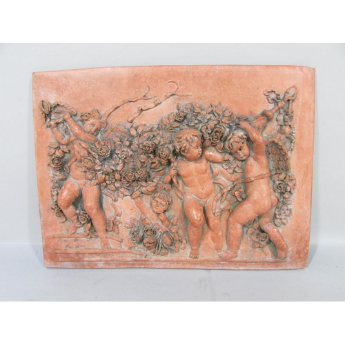 570 - A Terracotta wall plaque of four putti in relief frolicking amongst garlands of flowers, bearing a s... 