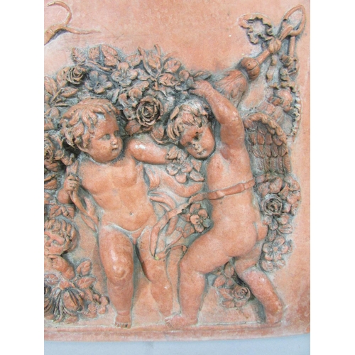 570 - A Terracotta wall plaque of four putti in relief frolicking amongst garlands of flowers, bearing a s... 