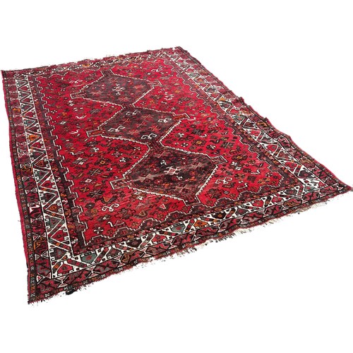 1757 - A Persian carpet with three interlocking medallions on a predominantly red ground, 240cm x 170cm app... 