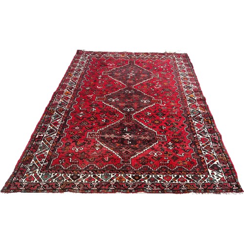 1757 - A Persian carpet with three interlocking medallions on a predominantly red ground, 240cm x 170cm app... 