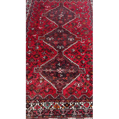 1757 - A Persian carpet with three interlocking medallions on a predominantly red ground, 240cm x 170cm app... 