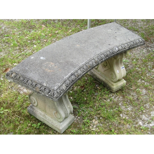 1038 - A weathered cast composition stone three sectional garden bench with curved slab seat raised on scro... 