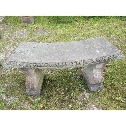 1038 - A weathered cast composition stone three sectional garden bench with curved slab seat raised on scro... 