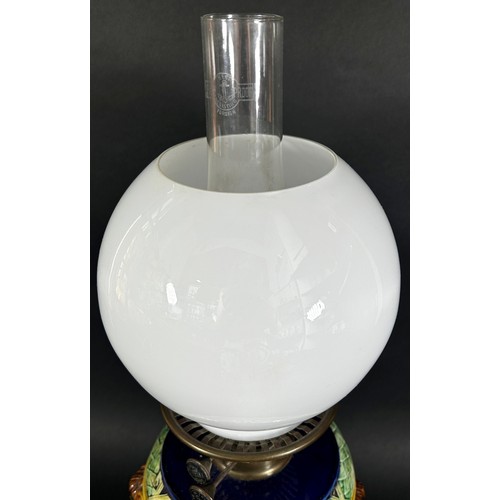 104 - A Victorian Majolica type ceramic oil lamp with loose cover, Duplex burner and opaque globular shade... 