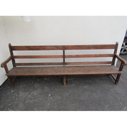 1672 - A long vintage stained pine chapel bench with triple railed back, open scrolled arms, tapered plank ... 