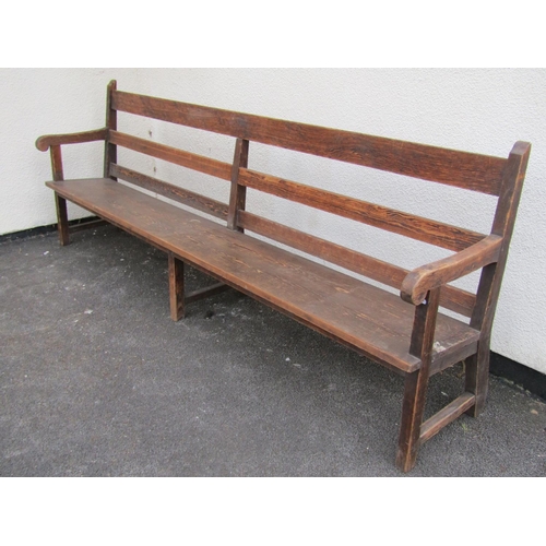 1672 - A long vintage stained pine chapel bench with triple railed back, open scrolled arms, tapered plank ... 