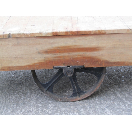 1675 - A vintage four-wheeled platform trolley, with hardwood boarded bed and cast iron fittings, (likely e... 