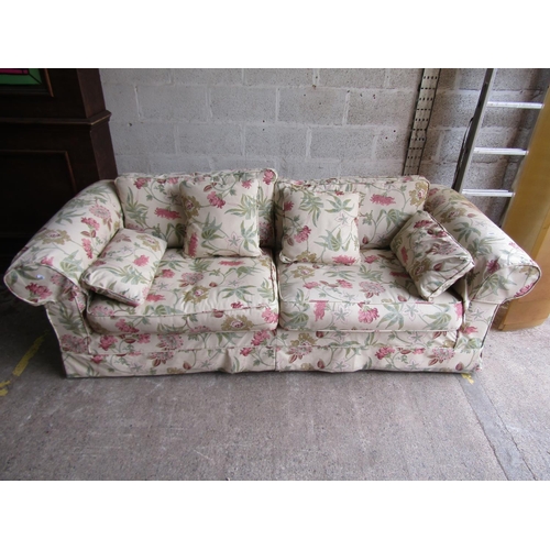 1695 - A traditional sofa with rolled arms, cream floral upholstery and loose seat and back cushions, appro... 