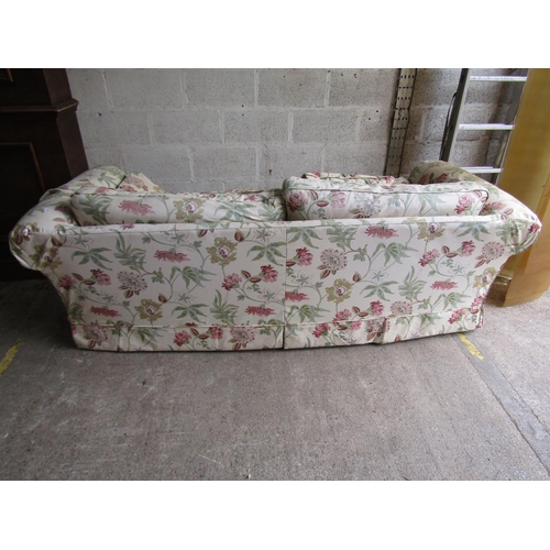 1695 - A traditional sofa with rolled arms, cream floral upholstery and loose seat and back cushions, appro... 