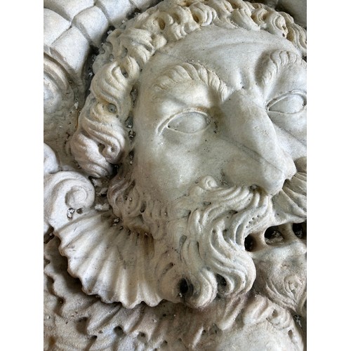 A large and impressive continental carved marble fountain head, detailing a mask of Poseidon above symmetrical stylised dolphins, 87 x 80cm