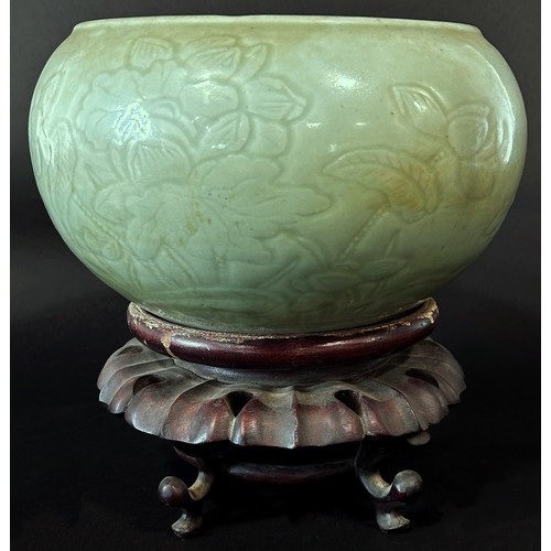 42 - A Chinese celadon glazed moulded porcelain alms bowl of open bulbous form, decorated with incised fl... 