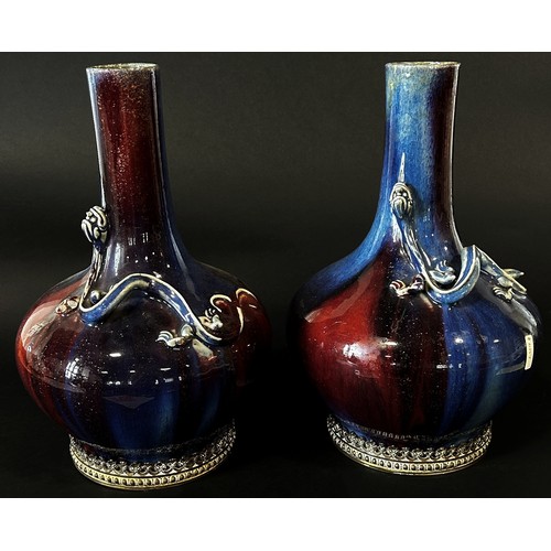 45 - A pair of Chinese Sang de Boeuf type bottle vases, each with drawn cylindrical necks over applied em... 