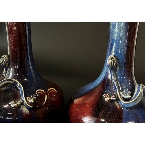 45 - A pair of Chinese Sang de Boeuf type bottle vases, each with drawn cylindrical necks over applied em... 