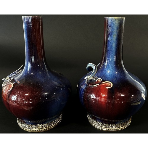 45 - A pair of Chinese Sang de Boeuf type bottle vases, each with drawn cylindrical necks over applied em... 