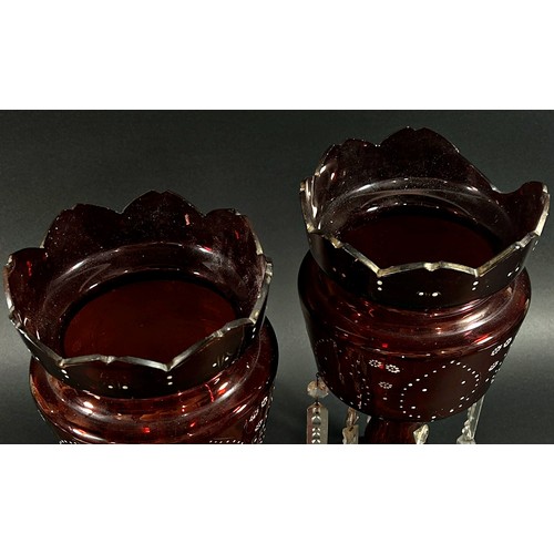 144 - A pair of Victorian red glass table lustres with enamelled detail and hanging clear cut prism drople... 