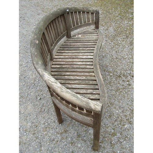 1151 - A weathered teak banana shaped garden bench with slatted seat and back, 160 cm long