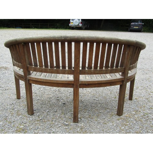 1151 - A weathered teak banana shaped garden bench with slatted seat and back, 160 cm long